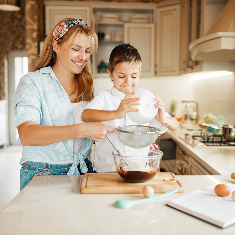 Mãe e filho misturando chocolate derretido numa tigela