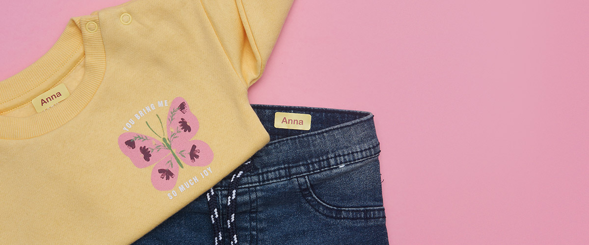 Jeans e um moletom com etiquetas My Nametags anexadas em um fundo rosa