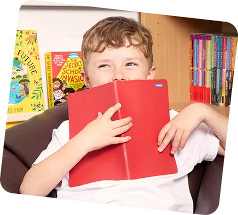 menino de escola segurando o livro vermelho na frente do rosto
